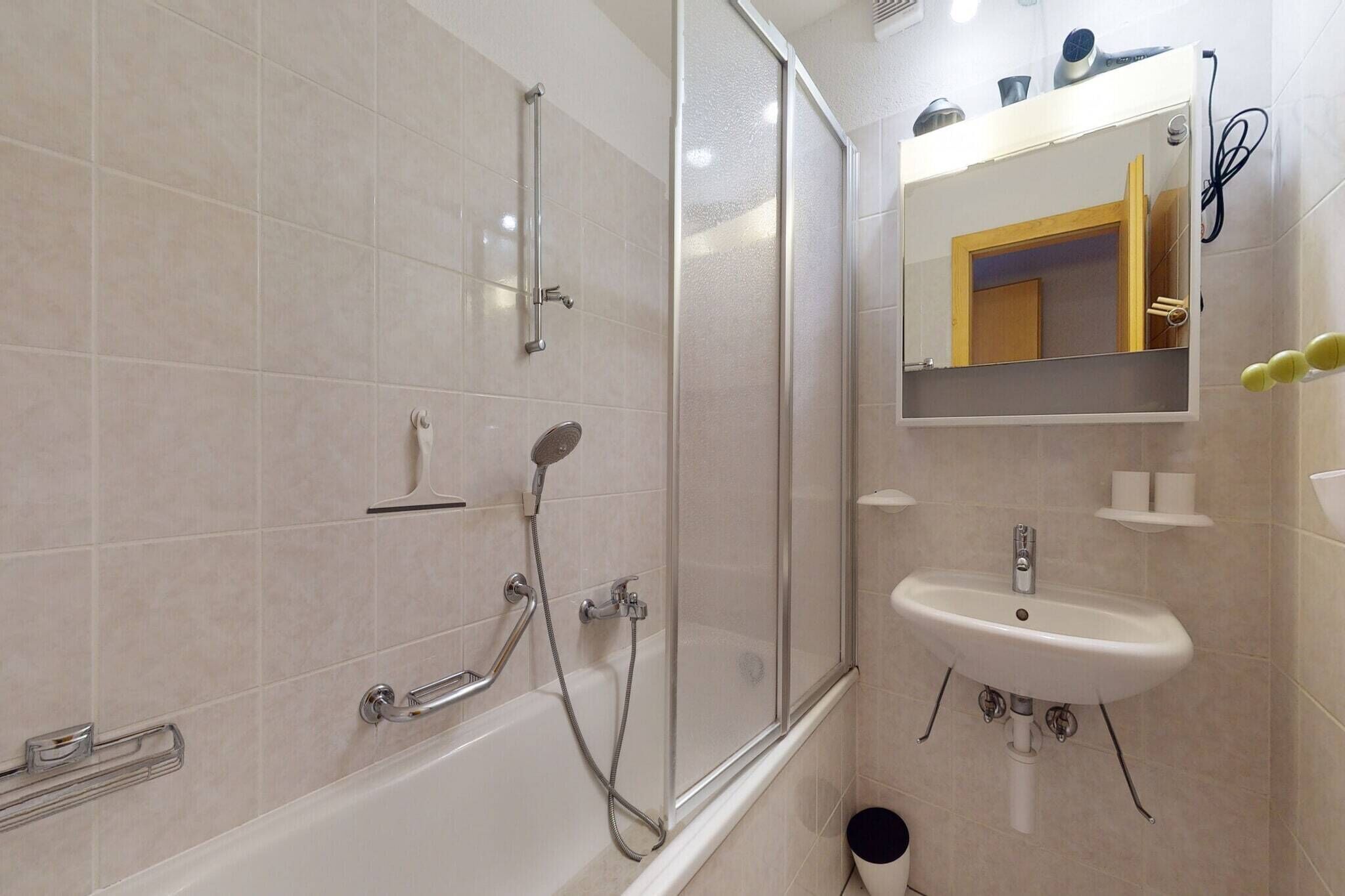A modern bathroom with a glass shower enclosure, a white sink, and a mirror above it.