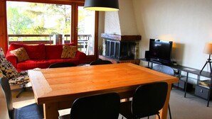 A cozy living room with a wooden table, black chairs, a red sofa, and a fireplace. - Apartment in Veysonnaz near Cable Car (Veysonnaz)