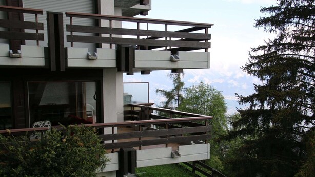 A modern two-story building with a balcony, surrounded by greenery and trees. - Apartment in Veysonnaz near Cable Car (Veysonnaz)