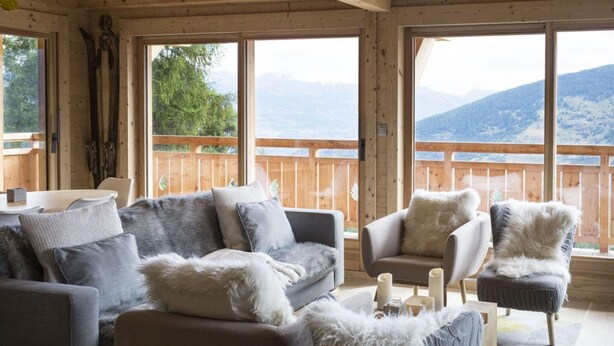 A cozy room with a sofa, armchairs, and a wooden deck with a view of mountains. - Chalet in Les Masses with garden (Les Masses)