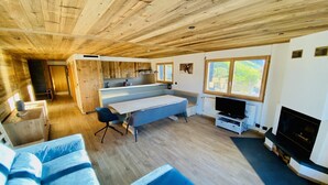 A spacious living area with a wooden ceiling, a built-in kitchen, a large window, and a fireplace. - Apartment in Veysonnaz near Ski Lift (Veysonnaz)