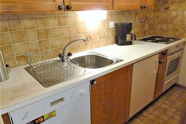 A kitchen with a stainless steel sink, a coffee maker, and a dishwasher.
