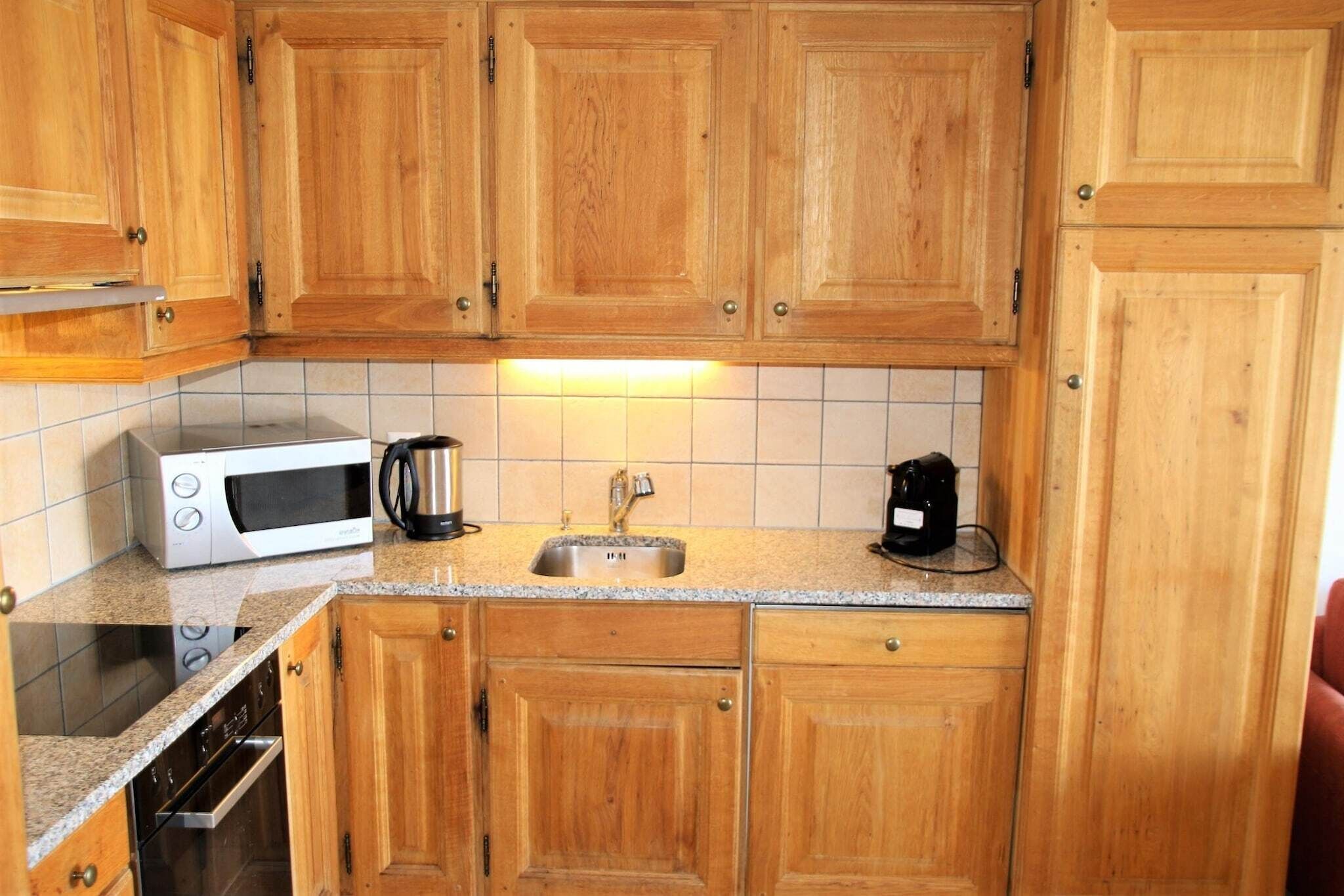 A kitchen with wooden cabinets, a microwave, a coffee maker, and a sink.