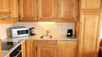 A kitchen with wooden cabinets, a microwave, a coffee maker, and a sink.