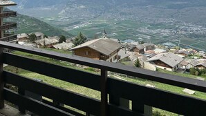 Uma aldeia montanhosa com casas tradicionais, uma igreja e vista para o vale.