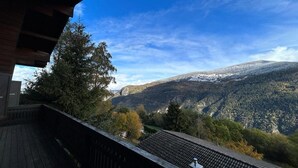 A view from a balcony overlooking a valley with snow-capped hills and dense forest. - Chalet in Vex near Les Masses Chairlift (Vex)