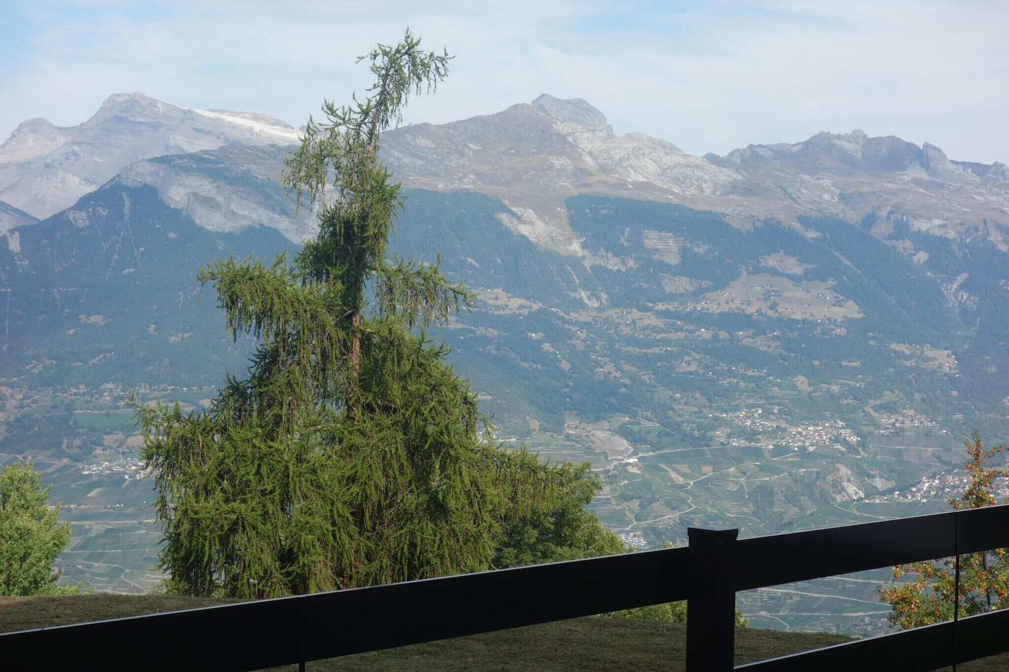 Un paysage de montagne avec une clôture en bois au premier plan.