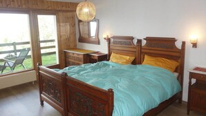 Un dormitorio con una cama de madera, una mesita de noche, una lámpara colgante y una ventana con vistas al exterior.