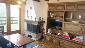 Una sala de estar acogedora con chimenea, televisor y una estantería llena de juegos de mesa.