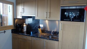 A kitchen with wooden cabinets, a black countertop, a stainless steel sink, a microwave, and a coffee maker.