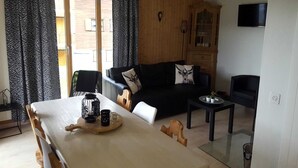 A living room with a sofa, a dining table with a tray, and a television.