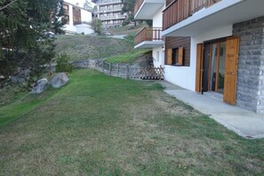 A modern building with a stone facade, wooden shutters, and a small balcony. - Mountain Escape with Fireplace (Veysonnaz)