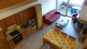 Um espaço compacto com cozinha, sala de jantar e sofá.