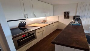 A modern kitchen with white cabinets, a black countertop, and stainless steel appliances. - Flat in Veysonnaz near Ski Lift & Valley Views (Veysonnaz)