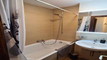 A bathroom with a bathtub, shower, and sink.