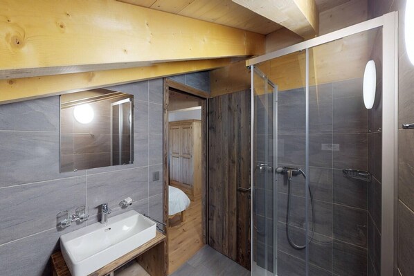 A modern bathroom with a wooden vanity, a large mirror, and a glass-enclosed shower.