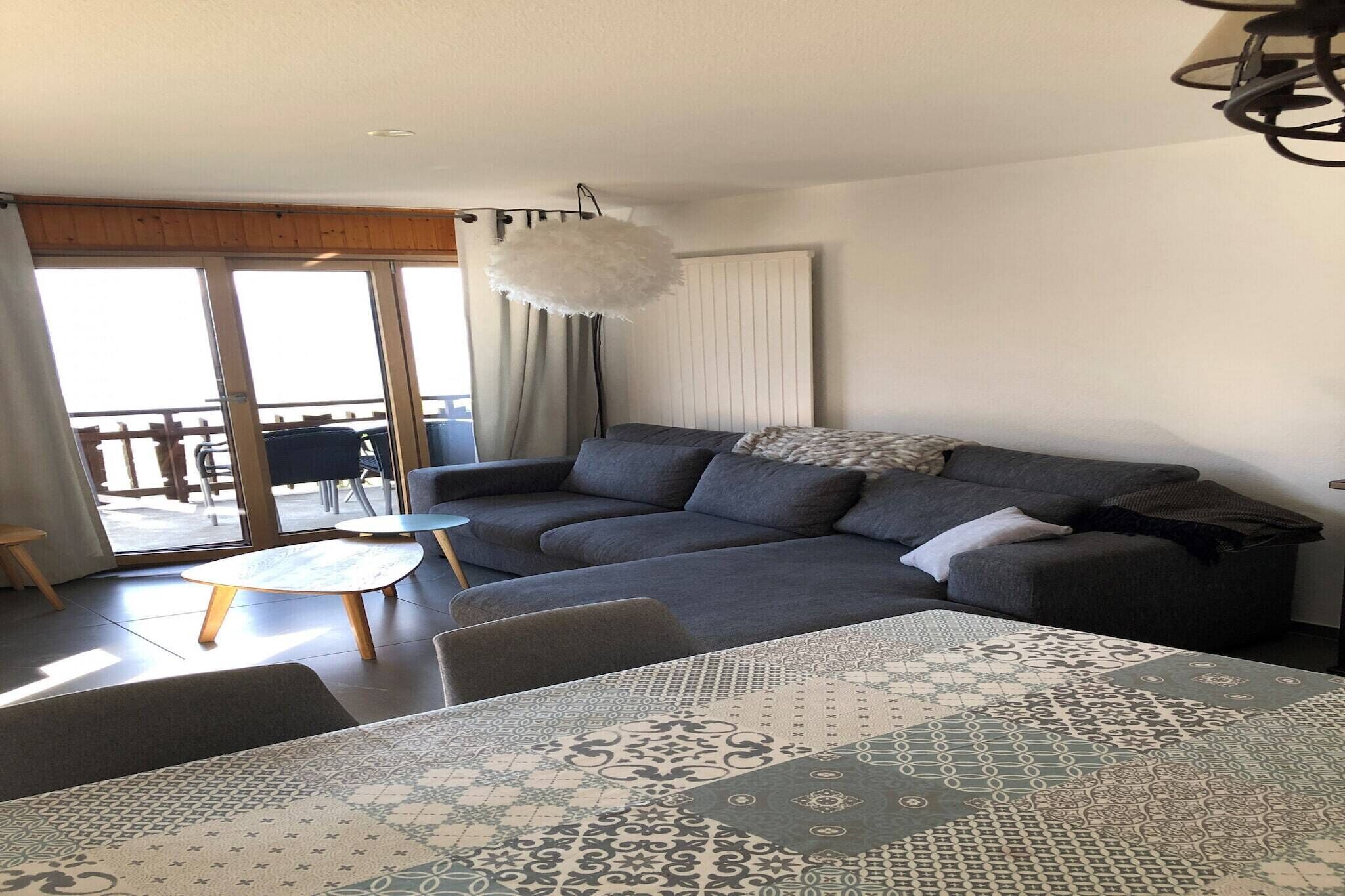 Een moderne woonkamer met een modulaire bank, een ronde salontafel en een kamerkleed met een patroon.