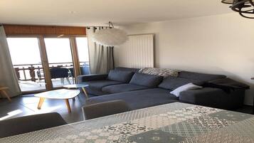 Een moderne woonkamer met een modulaire bank, een ronde salontafel en een kamerkleed met een patroon.