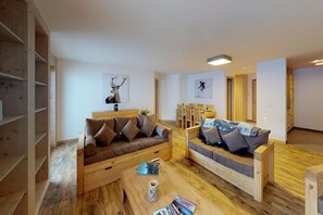 A modern living room with two sofas, wooden flooring, and a bookshelf. - Pleasant apartment in Versonnaz (Veysonnaz)