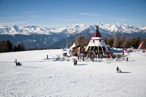 A snow-covered ski slope with a teepee structure and a ski lift in the background.