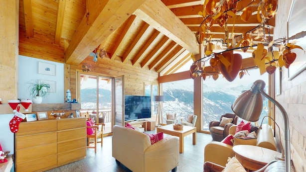A cozy cabin interior with wooden beams, a sofa, a dining table, and a TV. - Lush chalet in Heremence with sauna (Hérémence)