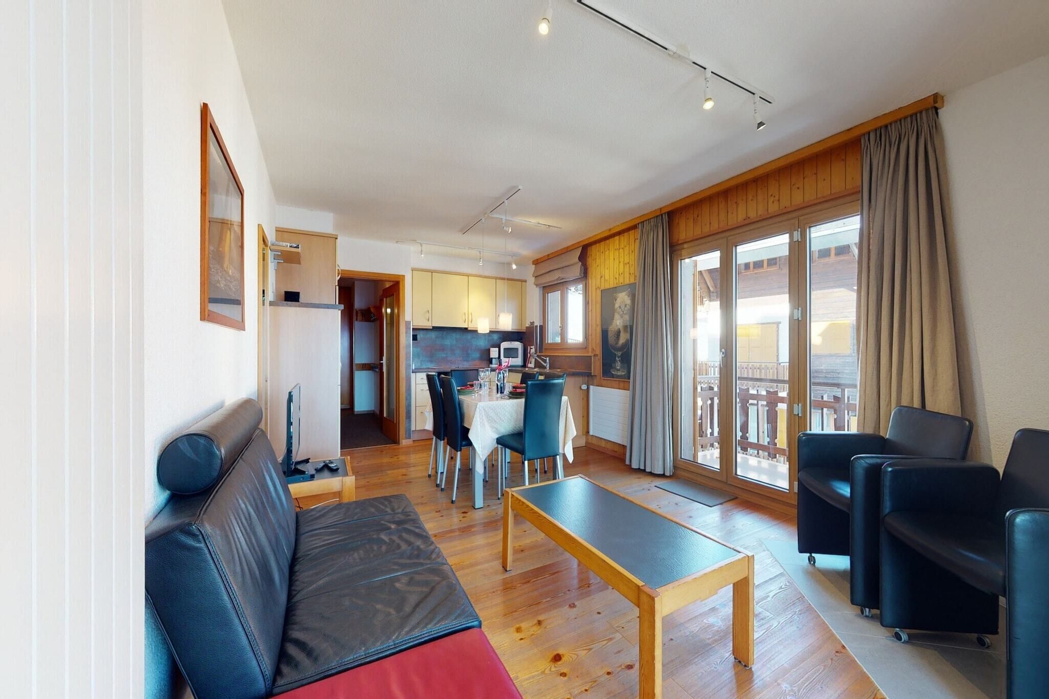 Een moderne woonkamer met een bank, een eettafel en een keuken op de achtergrond.