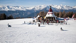Pista de esquí nevada con una estructura tipi y un telesilla al fondo.
