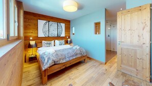 Un dormitorio con una cama de madera, un cuadro abstracto grande en la pared y una puerta de madera.