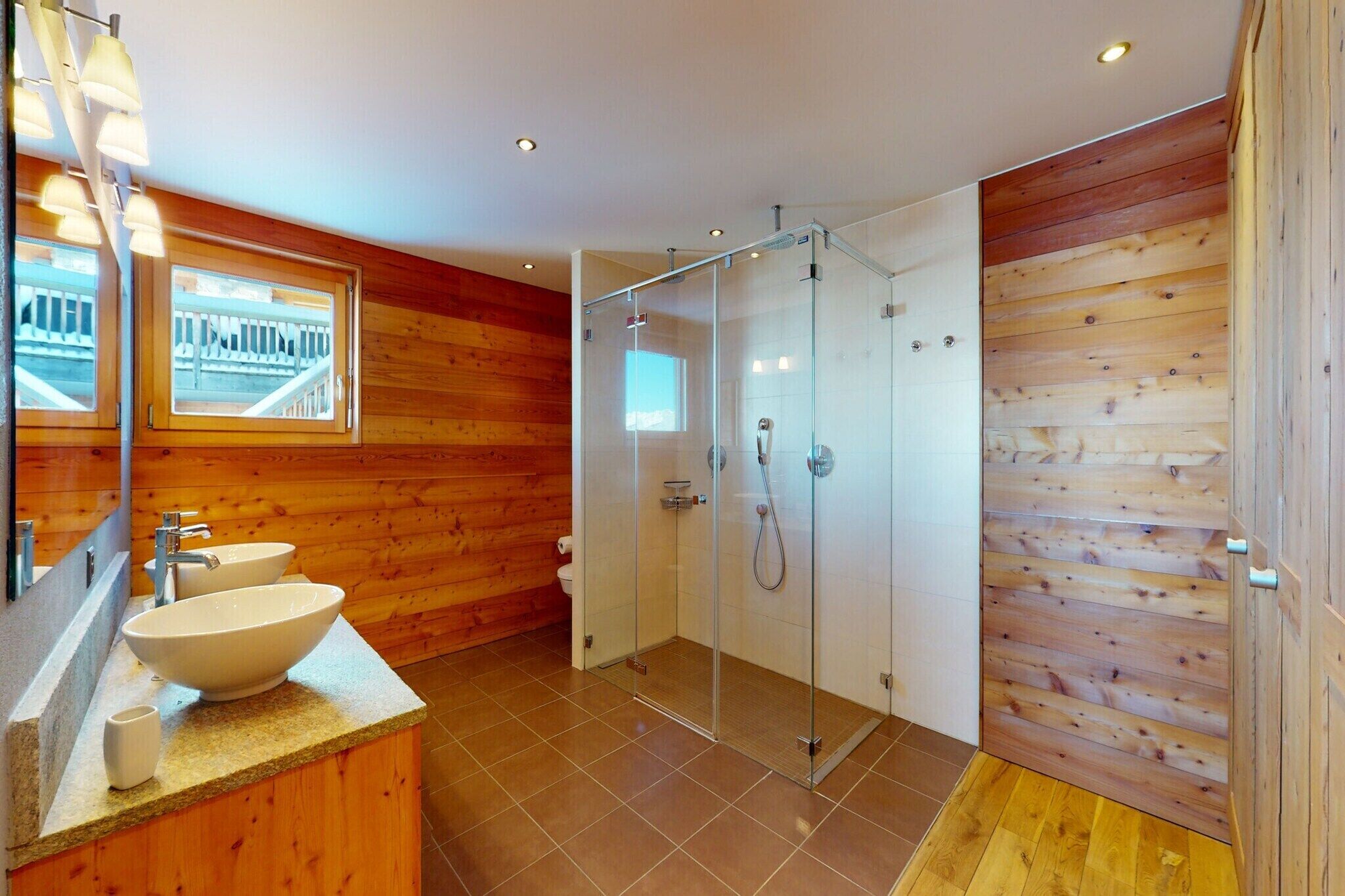 A modern bathroom with a wooden interior, a glass shower enclosure, and a large sink with a mirror above it.