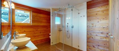 A modern bathroom with a wooden interior, a glass shower enclosure, and a large sink with a mirror above it.