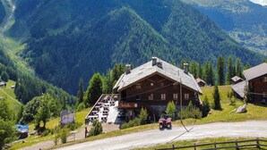A mountain lodge with a large wooden structure, a ski lift, and a view of surrounding forested mountains. - Apartment in Nendaz on ski slopes (Haute-Nendaz)