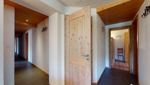 A hallway with wooden floors, a wooden door, and a chair in the background. - Apartment in Nendaz on ski slopes (Haute-Nendaz)
