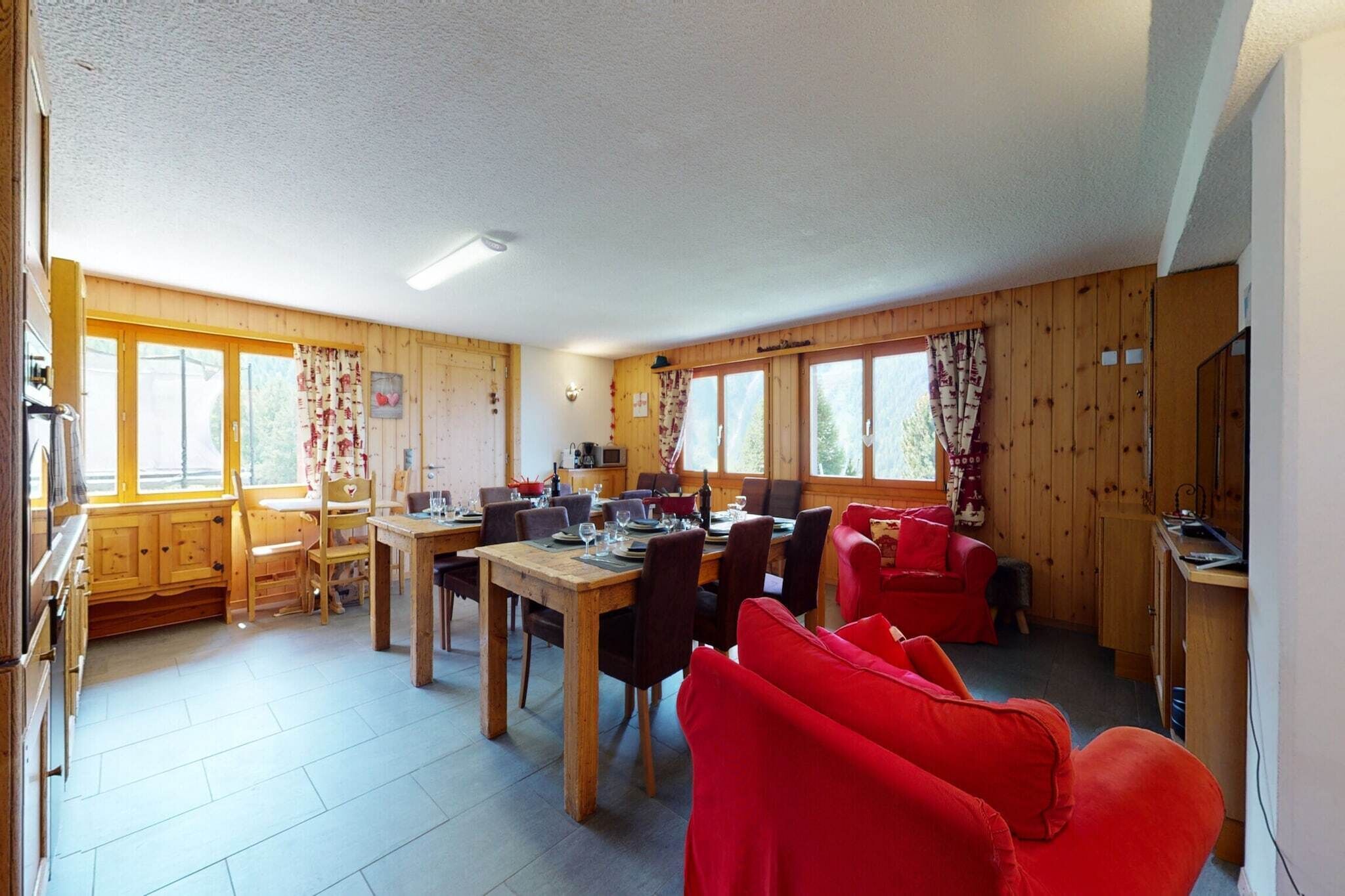 Uma cabana aconchegante com sala de jantar, cozinha e sala de estar com mobiliário vermelho.