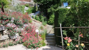 Un jardín con un muro de piedra, una valla de madera y una escalera que sube.
