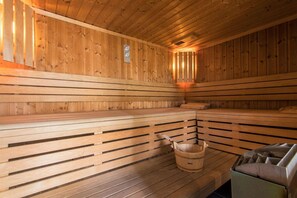 Eine Holzsauna mit Bänken und einem Holzeimer.