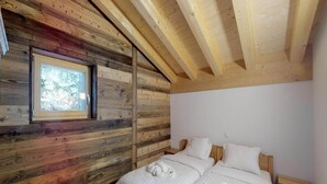 A wooden cabin bedroom with a bed, a window, and a wooden ceiling. - Modern apartment with balcony, ski access (Veysonnaz)