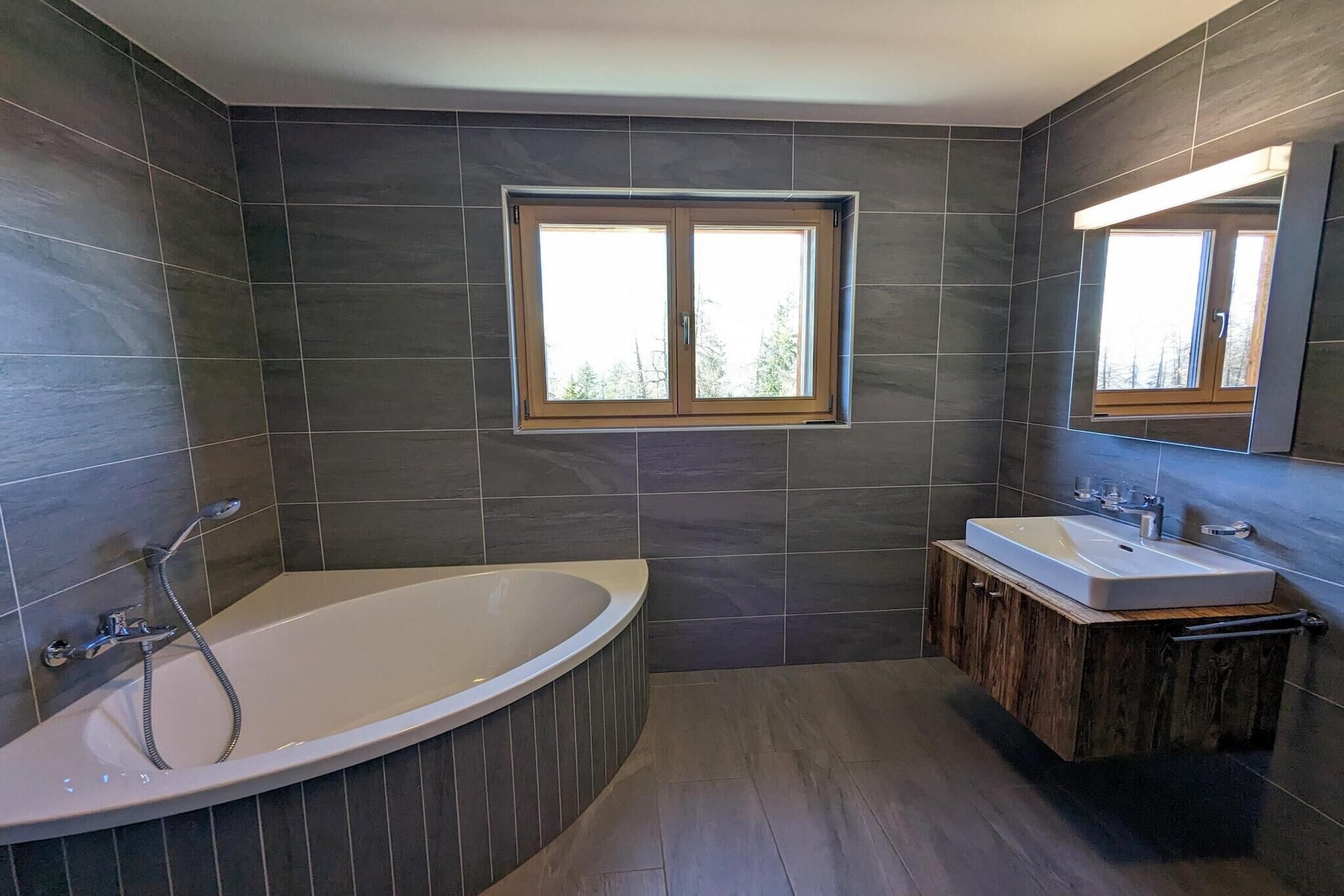 Une salle de bain moderne avec une baignoire sur pieds, un meuble-lavabo avec un miroir et une fenêtre laissant entrer la lumière naturelle.