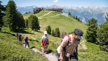 A group of hikers on a mountain trail with a view of a building and mountains in the background.