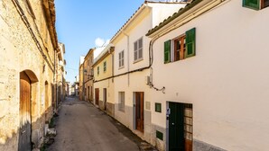 A narrow street lined with historic buildings, featuring arched doorways and shuttered windows.