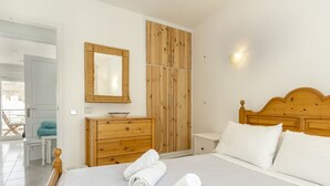 A bedroom with a wooden headboard, a large mirror, a wooden wardrobe, and a bedside table.