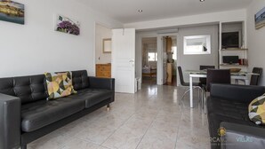 A modern living room with a sofa, a dining table, and a kitchen area.