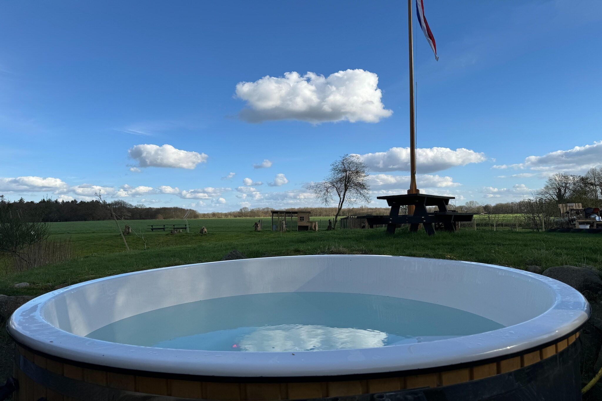 Ein Whirlpool in einer grünen Umgebung mit blauem Himmel und einer Fahnenstange.