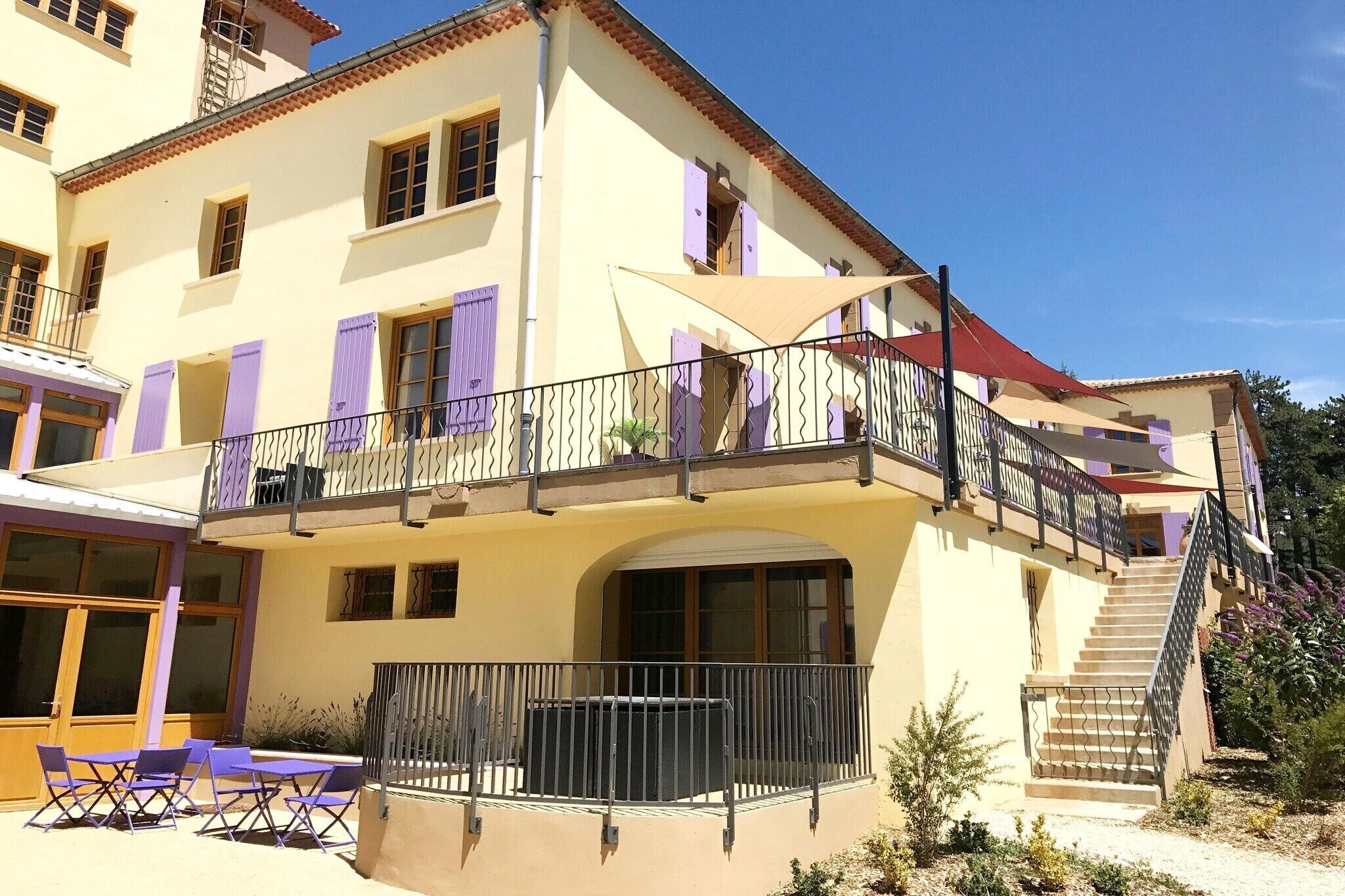 A two-story building with a balcony, outdoor seating, and a staircase.