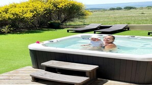 A hot tub with a wooden deck, a small step, and a view of a grassy field and trees. - Château Comfort in Provence (Ferrassières)