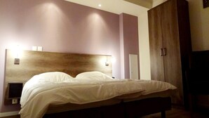 A bedroom with a wooden headboard, a bed with white bedding, a bedside table, and a wardrobe. - Château Comfort in Provence (Ferrassières)