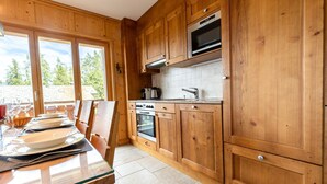 Una cocina de madera con un ventanal grande, horno empotrado y microondas.
