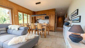 Una cocina moderna con armarios de madera, una zona de comedor con mesa y sillas, y un sofá con una manta de piel.