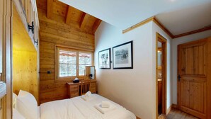 Ein Schlafzimmer mit Holzwandverkleidung, einem Bett, einem Schminktisch und zwei gerahmten Bildern an der Wand.