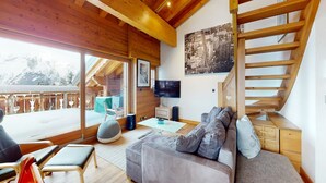 Ein modernes Wohnzimmer mit Holzboden, einem grauen Sofa, einem Flachbildfernseher und einer Treppe.