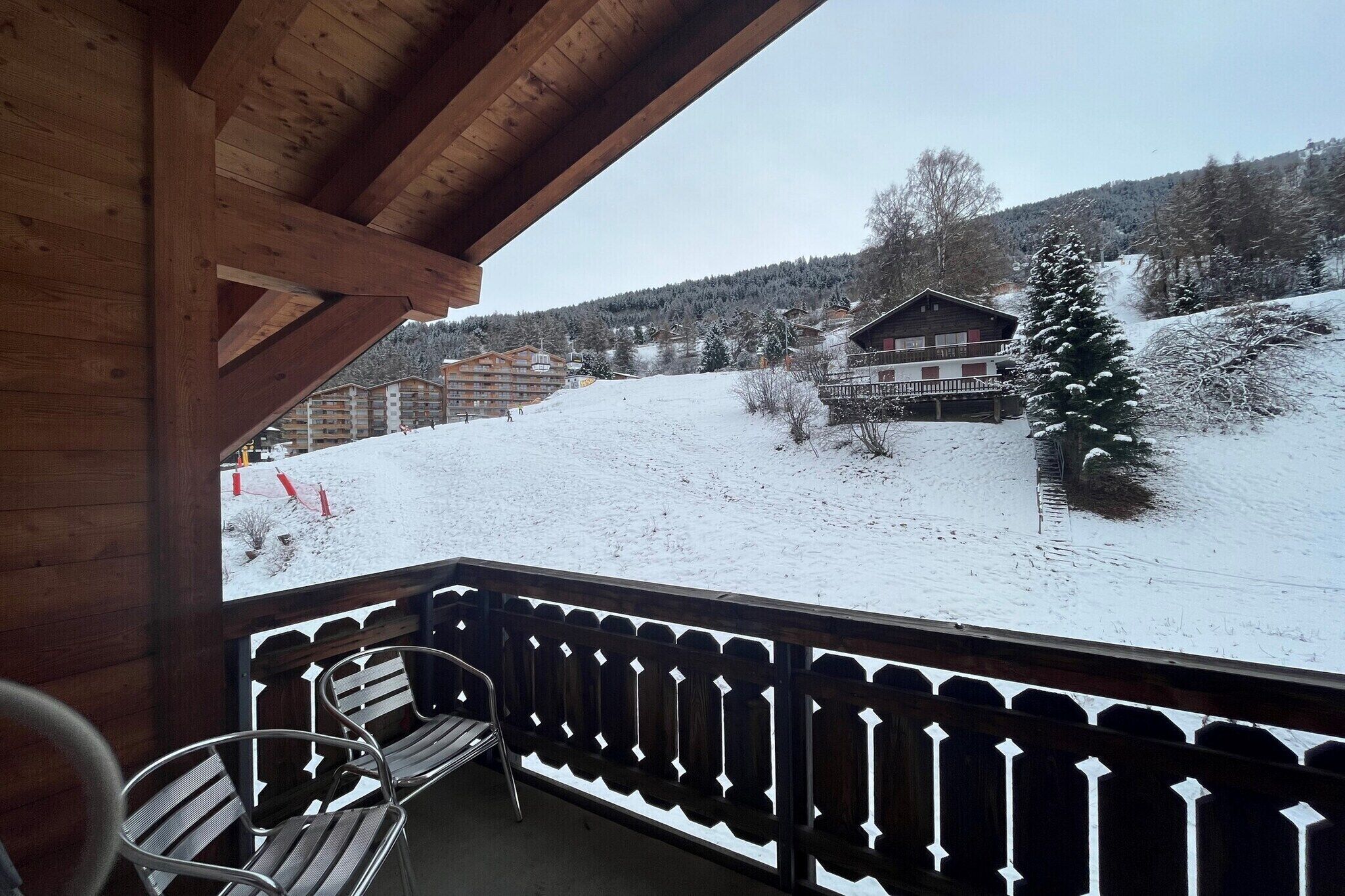 Ein Holzbalkon mit Blick auf eine verschneite Landschaft und Gebäude.
